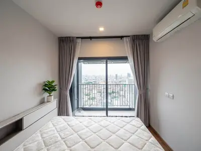 Modern bedroom with city view and balcony access in high-rise apartment