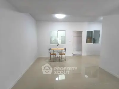 Spacious minimalist living room with tiled flooring and simple dining setup.