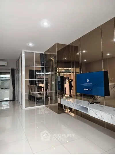 Modern living room with sleek mirrored walls and mounted TV in luxury apartment.