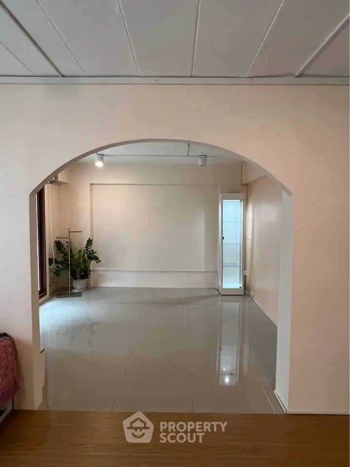 Spacious empty room with glossy tiled floor and archway, perfect for customization.