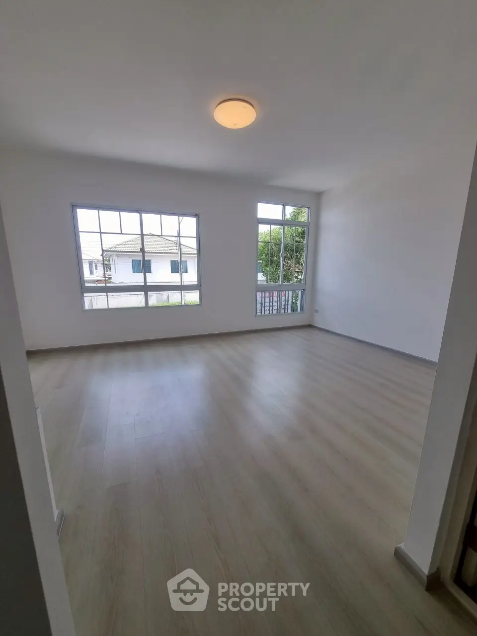 Spacious empty room with large windows and wooden flooring, perfect for customization.