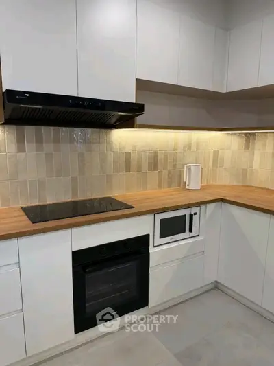 Modern kitchen with sleek cabinetry, built-in oven, and stylish backsplash