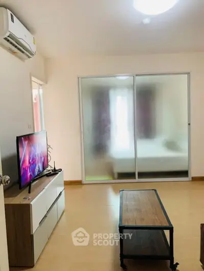 Modern living room with TV and sliding glass doors leading to bedroom