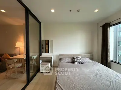 Modern bedroom with glass partition and cozy living area in a stylish apartment.