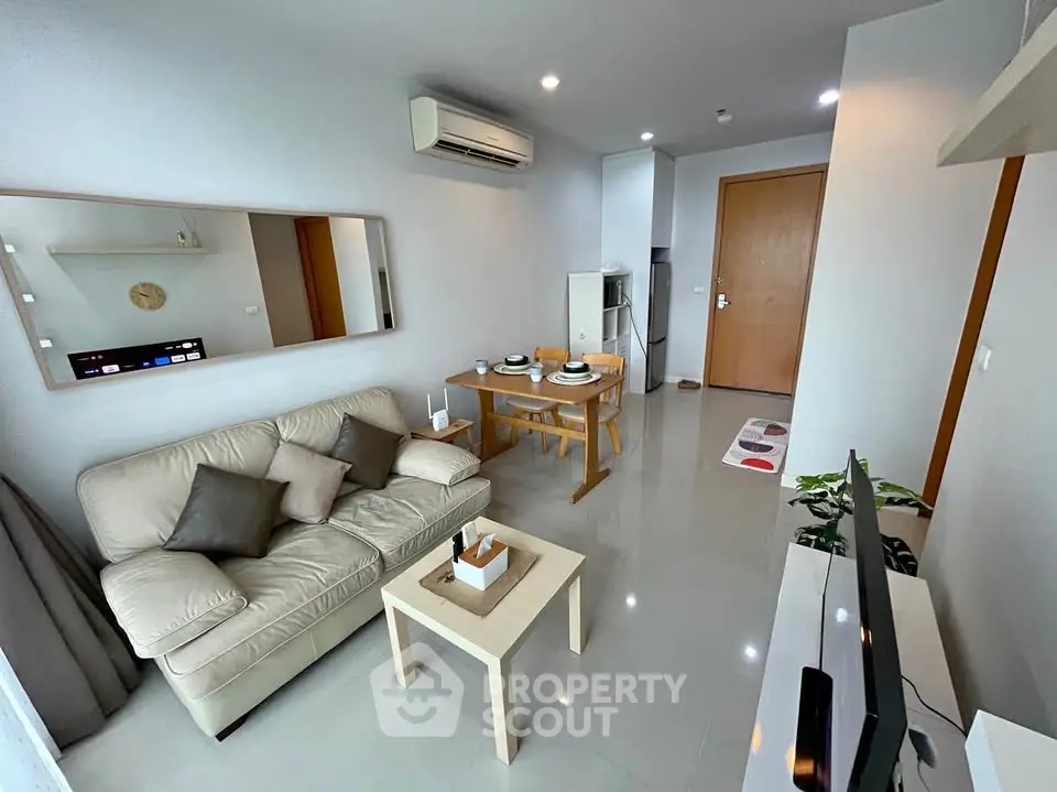 Modern living room with sleek furniture and dining area in open layout apartment.