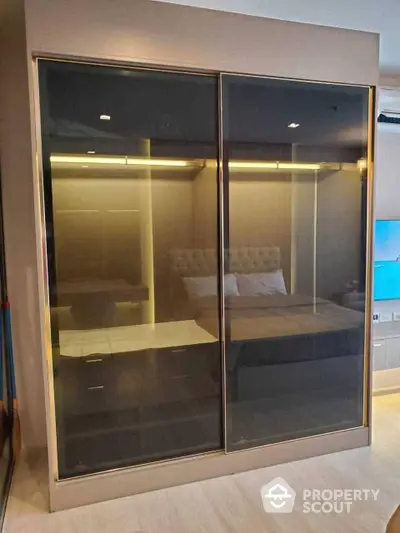 Elegant bedroom with mirrored sliding wardrobe doors reflecting a well-appointed interior, enhancing the sense of space and luxury.