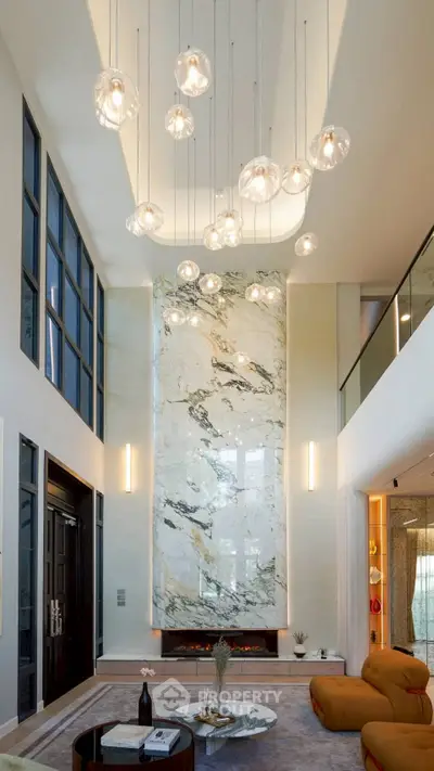 Luxurious modern living room with high ceilings, elegant lighting, and stunning marble fireplace feature wall.