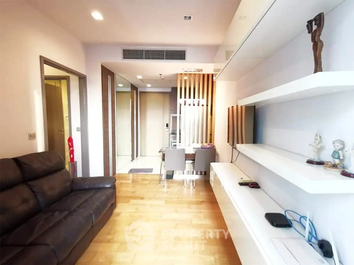 Modern living room with sleek design and wooden flooring, featuring a comfortable leather sofa and stylish shelving.