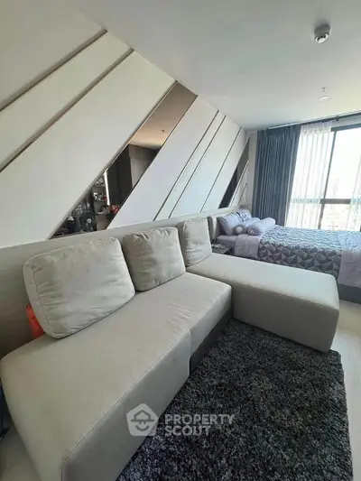Modern bedroom with stylish decor and cozy seating area, featuring large windows for natural light.