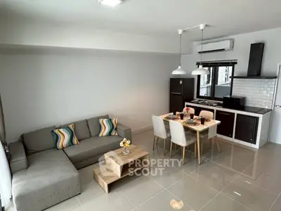 Modern open-plan living room with sleek kitchen and dining area, featuring stylish decor and ample natural light.