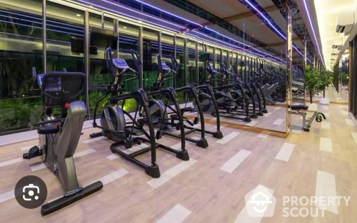 Modern gym with state-of-the-art exercise equipment and mirrored walls in luxury apartment complex.