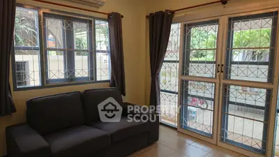 Cozy living room with large windows and garden view, perfect for relaxation.