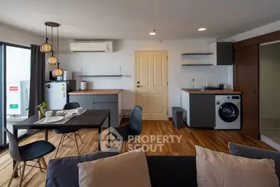 Modern open-plan living room with kitchen, featuring wooden floors and stylish furniture.