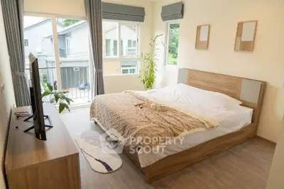 Cozy bedroom with large windows and modern decor, offering a serene view of the neighborhood.