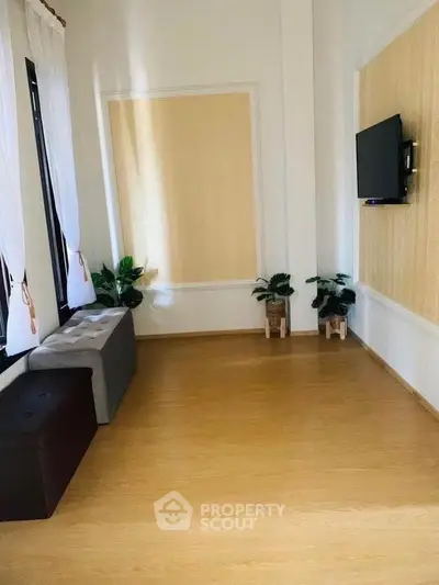Spacious living room with wooden flooring and wall-mounted TV, ideal for modern living.