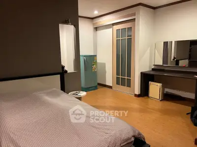 Spacious bedroom with modern decor and ample natural light, featuring a stylish sliding door and compact fridge.