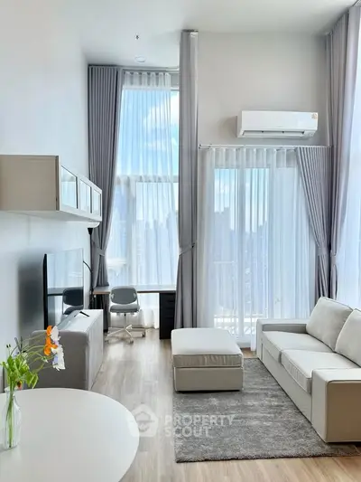 Modern living room with high ceilings, large windows, and stylish furniture in a bright apartment.