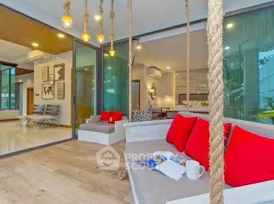 Luxurious modern living room with swing seat and vibrant red cushions, open layout and stylish decor.