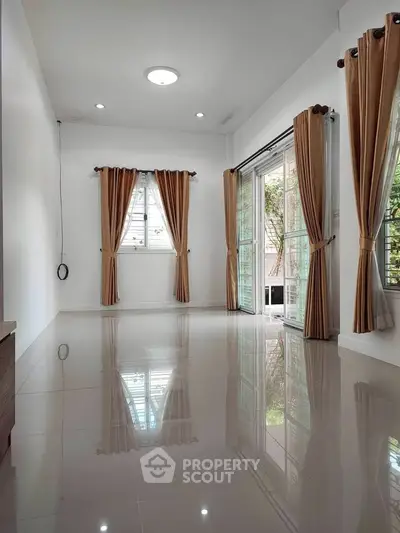 Spacious living room with large windows and elegant curtains, perfect for natural light lovers.