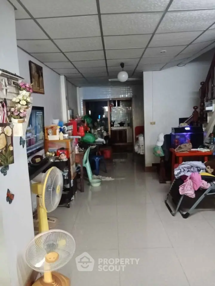 Spacious living area with tiled flooring and ceiling fan, ideal for family gatherings.