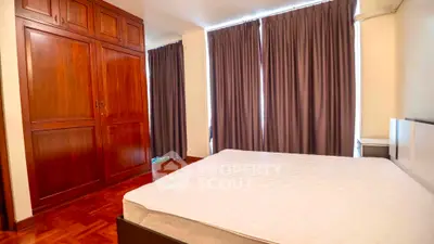 Spacious bedroom with wooden wardrobe and large windows for natural light.