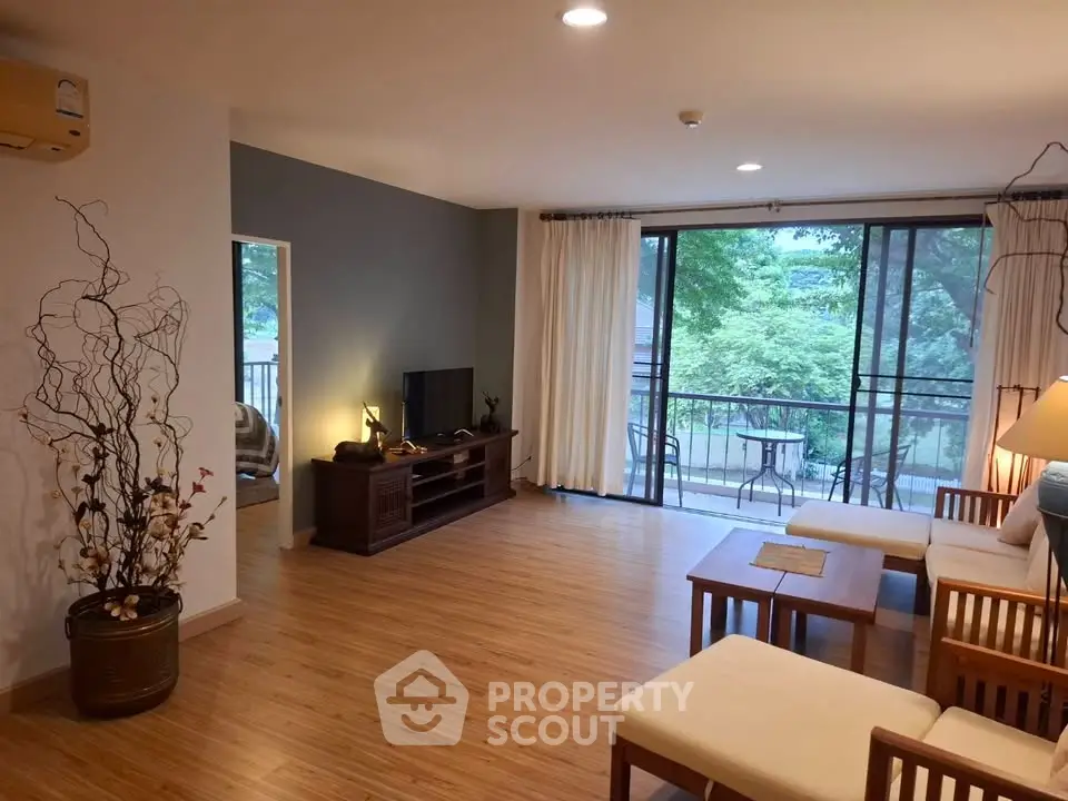 Spacious living room with wooden flooring and balcony view