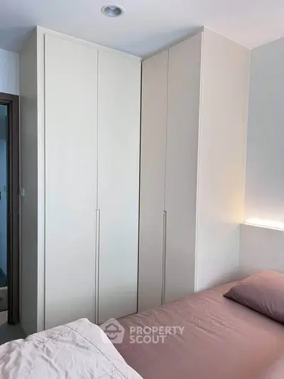 Modern bedroom with sleek built-in wardrobe and cozy bedding, perfect for stylish living.