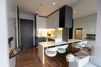 Sleek modern kitchen with integrated appliances, white countertops, and a breakfast bar with stylish seating in a luxurious apartment.