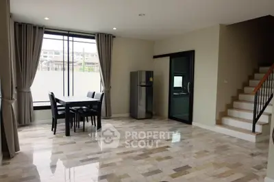 Spacious open-plan living area with modern dining set and sleek staircase