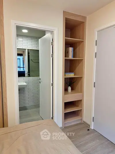 Modern bedroom with built-in shelves and en-suite bathroom in stylish apartment.