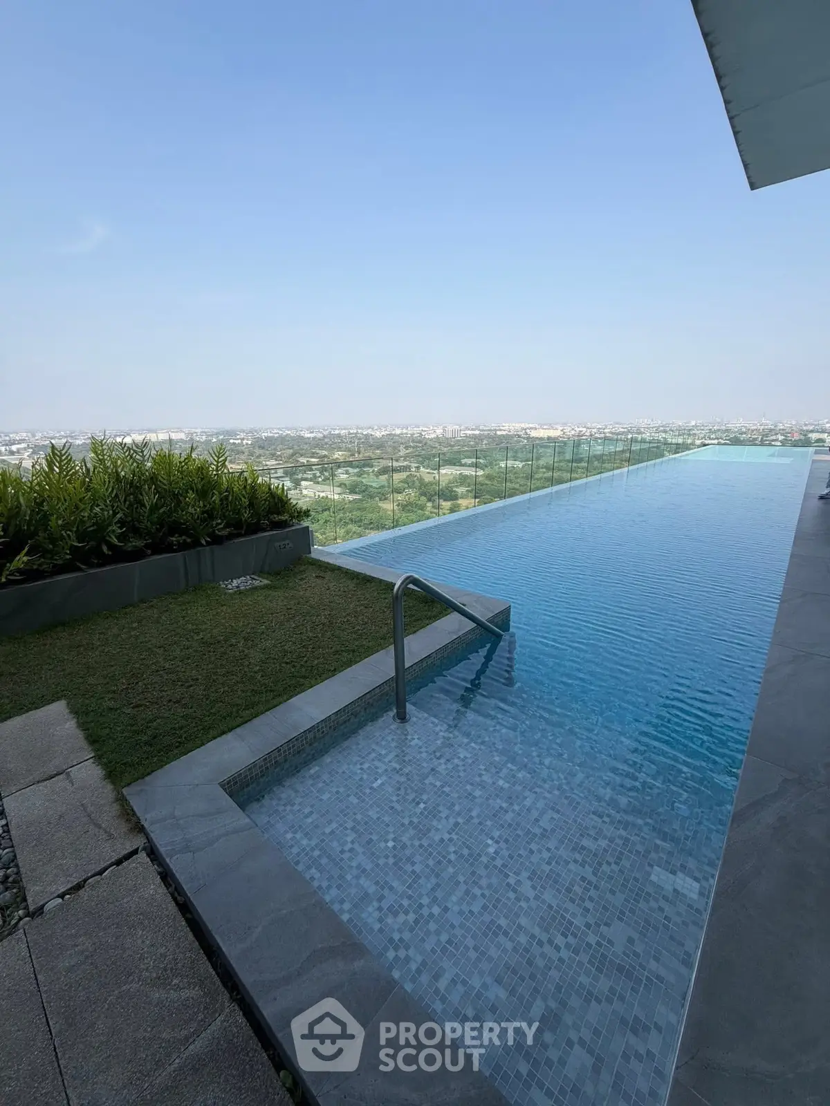 Luxurious rooftop infinity pool with stunning panoramic city views and lush greenery.