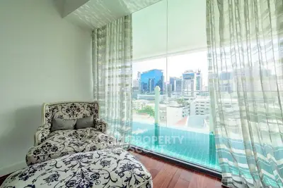 Luxurious living room with elegant armchair and stunning city view through large windows.