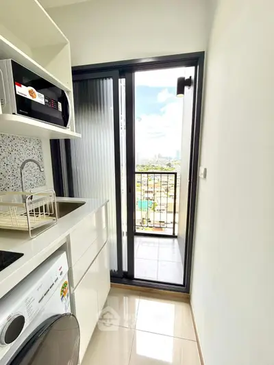 Modern kitchen with balcony view, featuring sleek appliances and bright natural light.