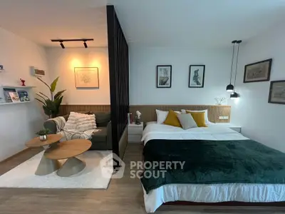 Modern studio apartment with stylish decor, featuring a cozy bed and a chic living area separated by a sleek partition.