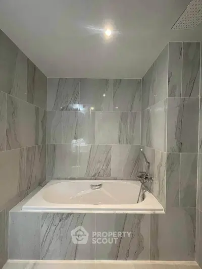 Luxurious bathroom with elegant marble tiles and a spacious bathtub, perfect for relaxation.