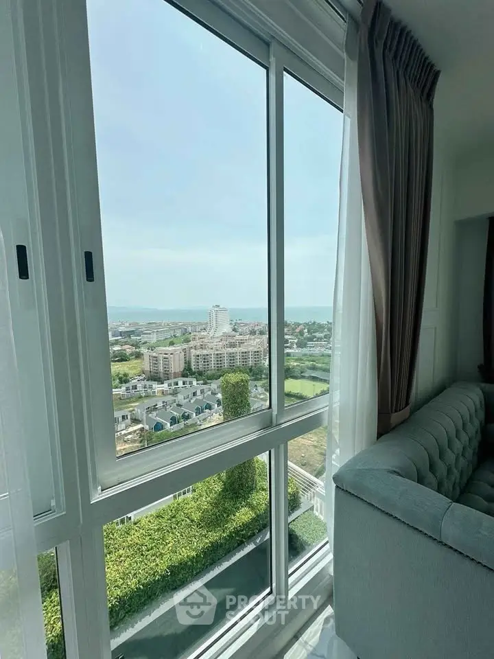 Stunning high-rise apartment view with expansive windows overlooking cityscape and greenery.