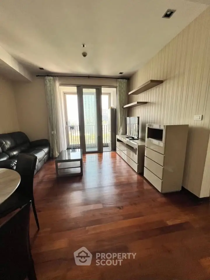 Modern living room with hardwood floors, sleek furniture, and large windows offering city views.