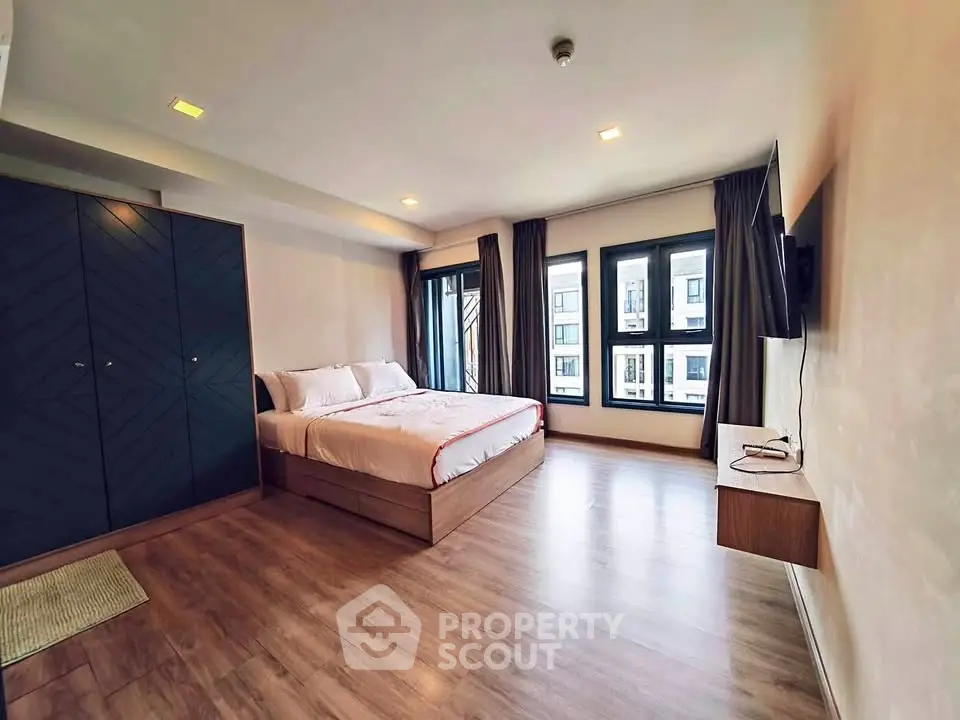 Spacious modern bedroom with large windows and stylish wooden flooring