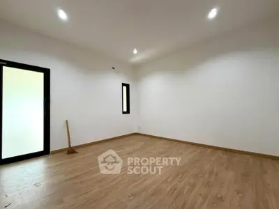 Spacious empty room with wooden flooring and bright lighting, ideal for customization.