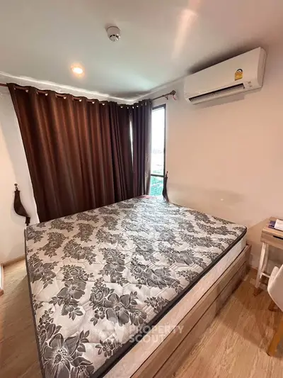 Cozy bedroom with large bed and air conditioning, featuring elegant curtains and wooden flooring.
