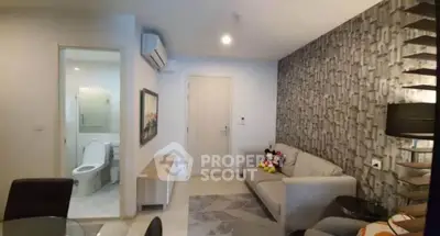 Modern living room with stylish decor and adjacent bathroom, featuring a cozy sofa and elegant lighting.