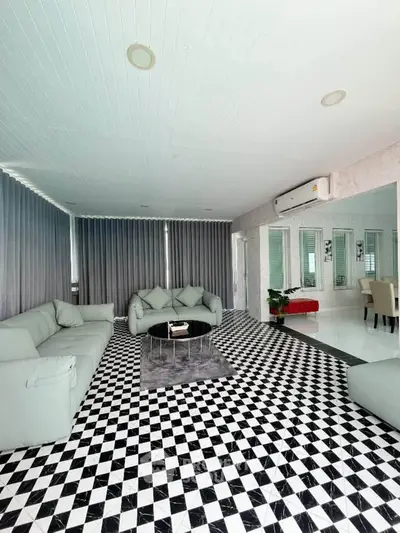 Spacious modern living room with stylish black and white checkered flooring and elegant gray sofas.