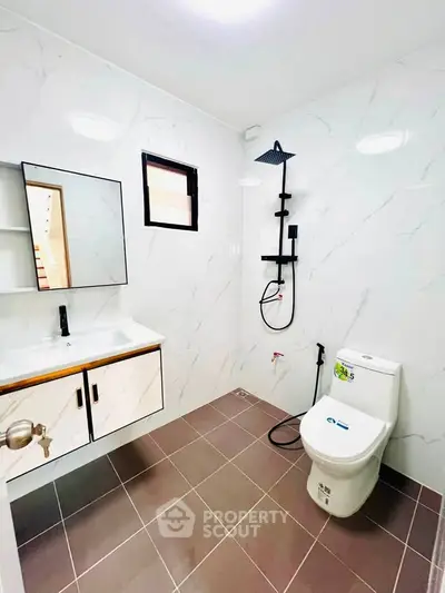 Modern bathroom with sleek fixtures and marble walls, featuring a rainfall shower and elegant vanity.