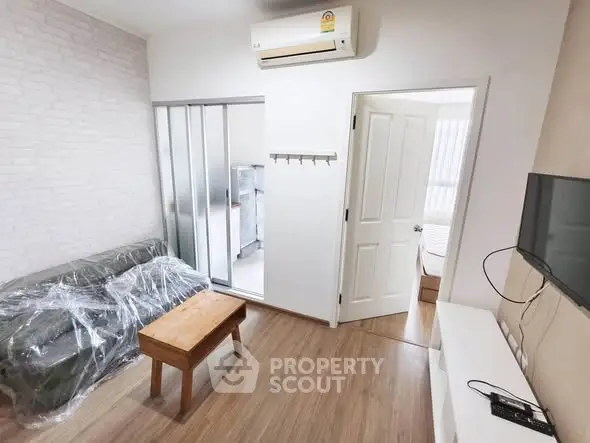 Modern living room with air conditioning and sliding glass doors leading to a bright bedroom.