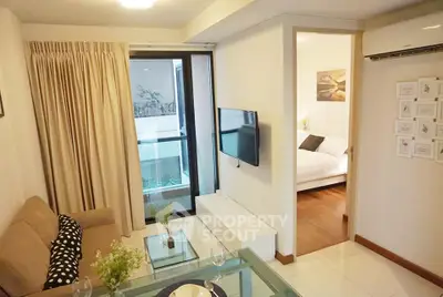 Modern living room with cozy sofa and TV, adjacent to a stylish bedroom.