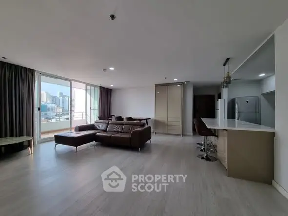 Spacious modern living room with open kitchen and city view balcony.