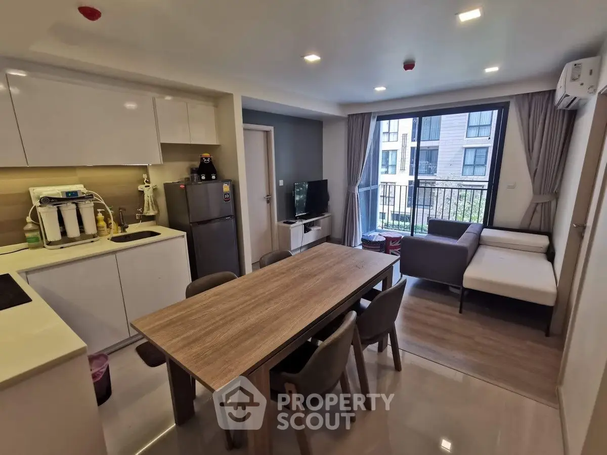 Modern open-plan kitchen and living area with dining table and balcony view.