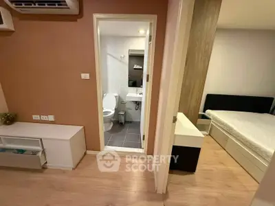 Modern apartment interior with bedroom and bathroom, featuring sleek design and wooden flooring.
