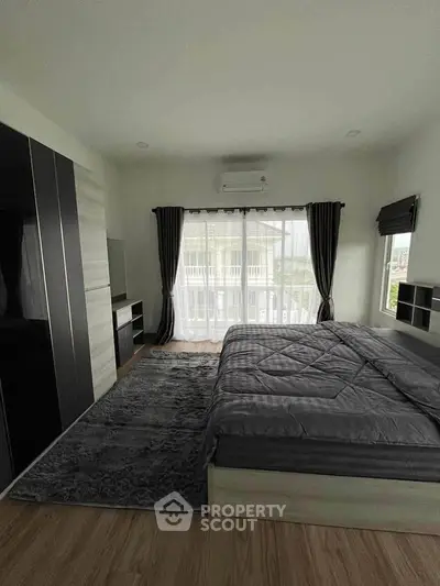 Spacious modern bedroom with large window and stylish furnishings