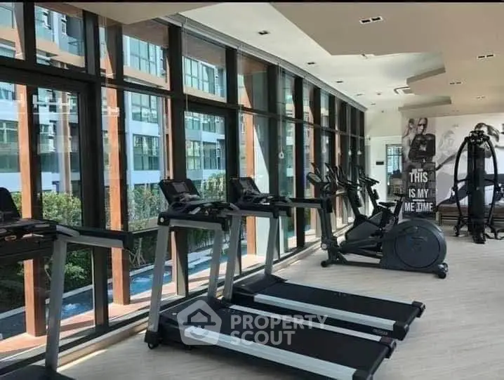 Modern gym with large windows and state-of-the-art equipment in a luxury apartment complex.